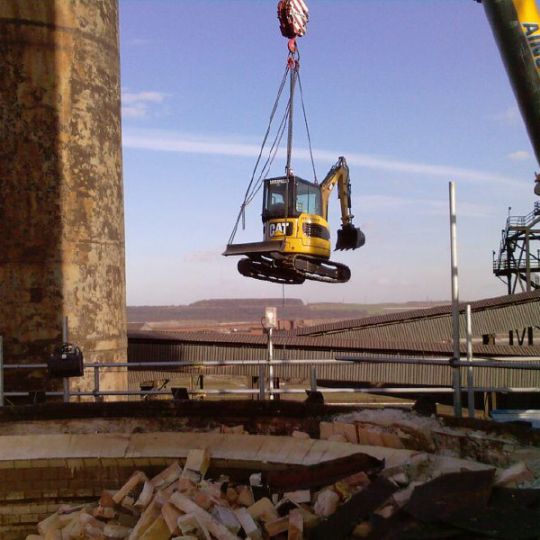 Ron Hull digger being lifted into place by crane at a demolition