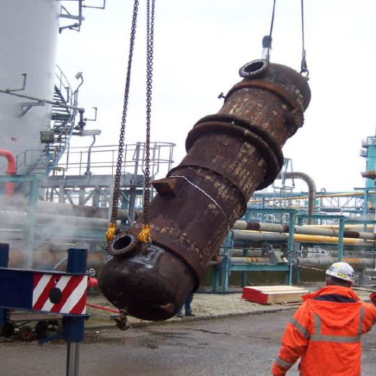 Industrial tank being moved by crane during decomissioning
