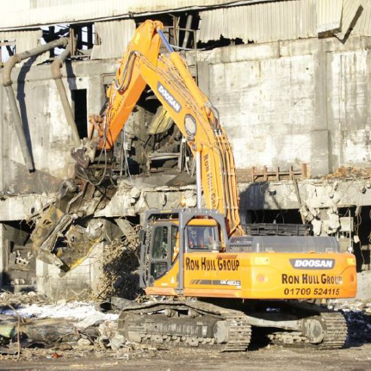 Building being demolished by machine